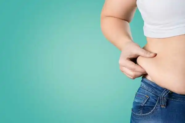 Image of woman pinching her love handles to show weight gain Owsestry